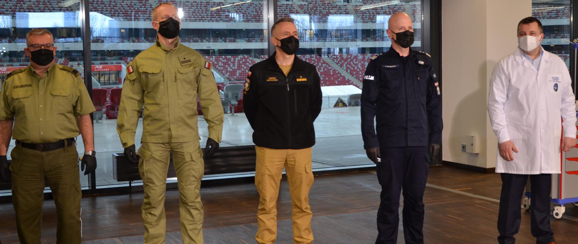 Zdjęcie przedstawia pięć osób, w tym Komendanta Głównego PSP na tle stadionu narodowego