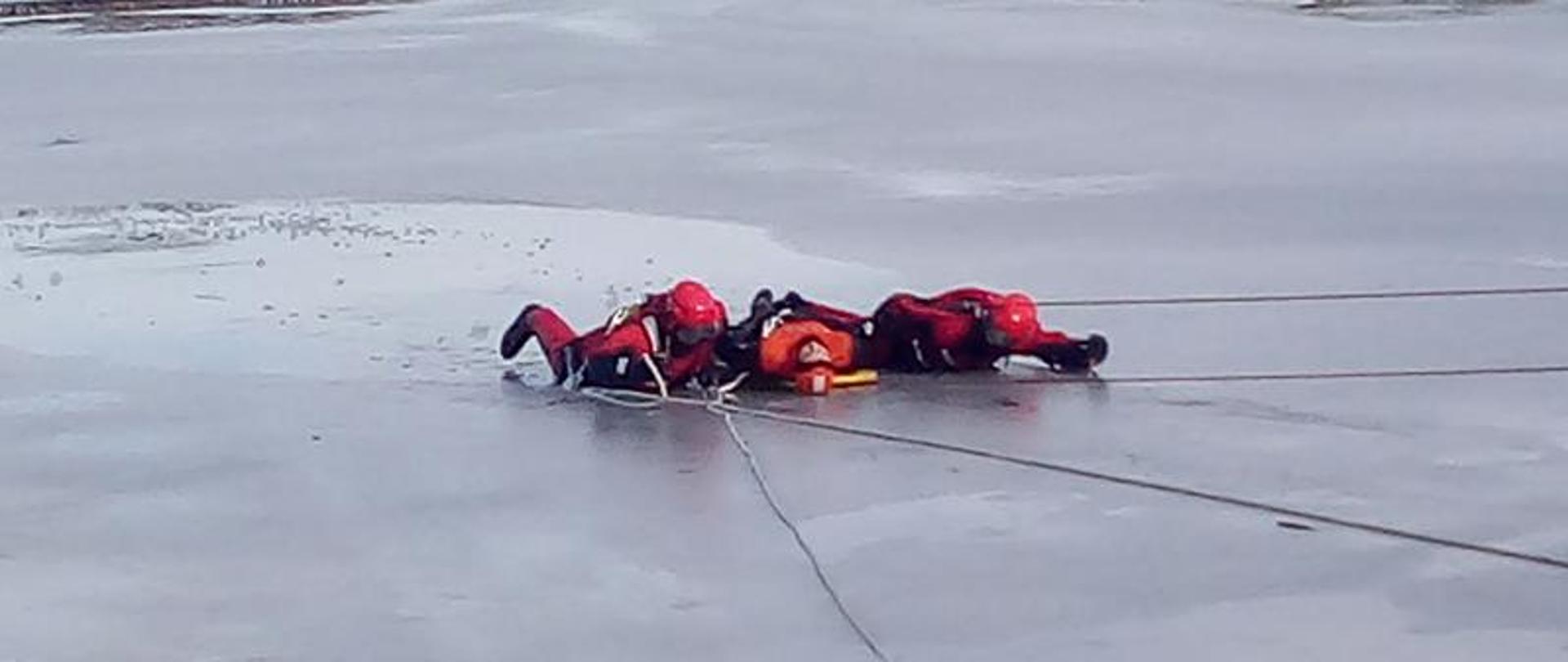 Strażacy holują leżąc poszkodowanego na desce do brzegu.