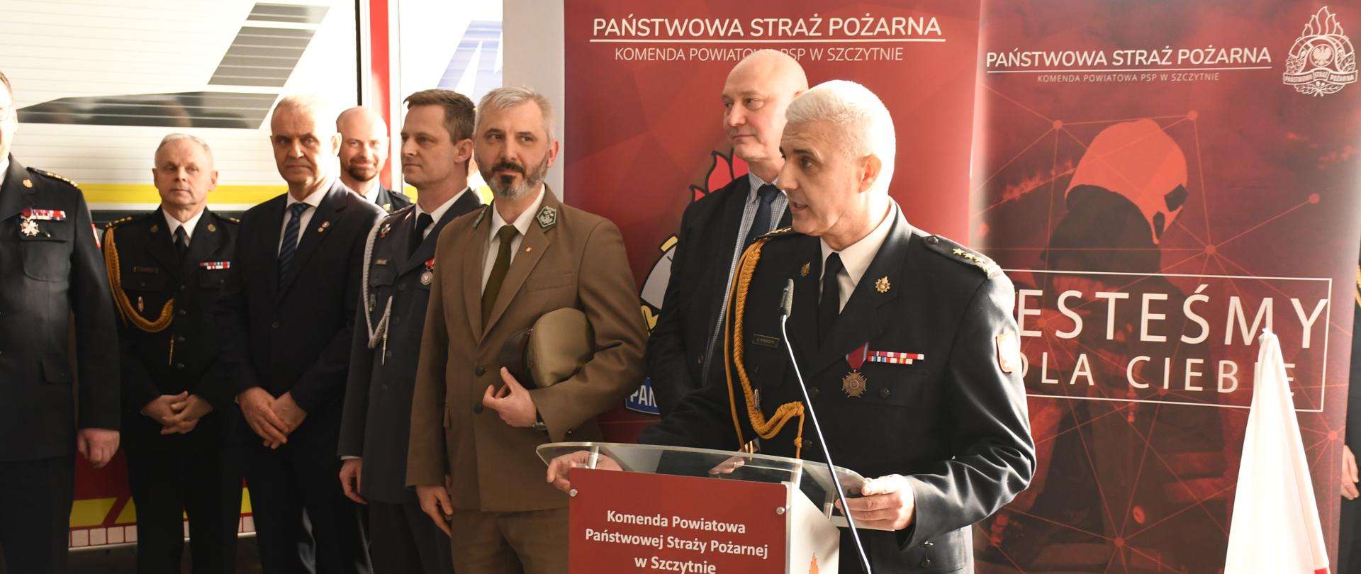 Zdjęcie przedstawia komendanta powiatowego st.bryg. Grzegorza Rybaczyka podczas uroczystej przemowy pożegnalnej