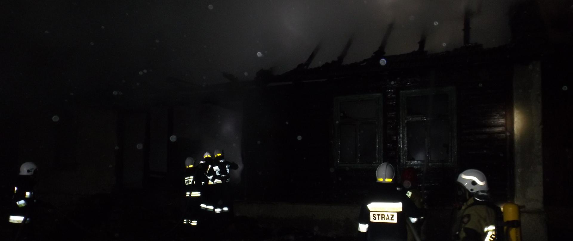 Na zdjęciu widać akcję gaśniczą. Ratownicy podają wodę do wnętrza płonącego budynku.