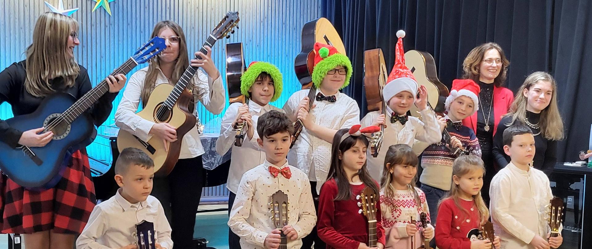 Galeria 21 zdjęć - uczniowie odświętnie ubrani grają na gitarach kolędy i pastorałki - 19.12.2025