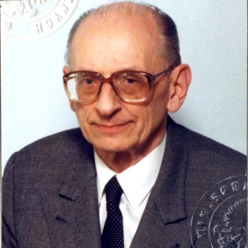 Władysław Bartoszewski kolorowy portret łysiejącego mężczyzny w okularach z grubymi oprawkami, siwe włosy, ciemna marynarka, ciemny krawat w drobne ciemne wzory.