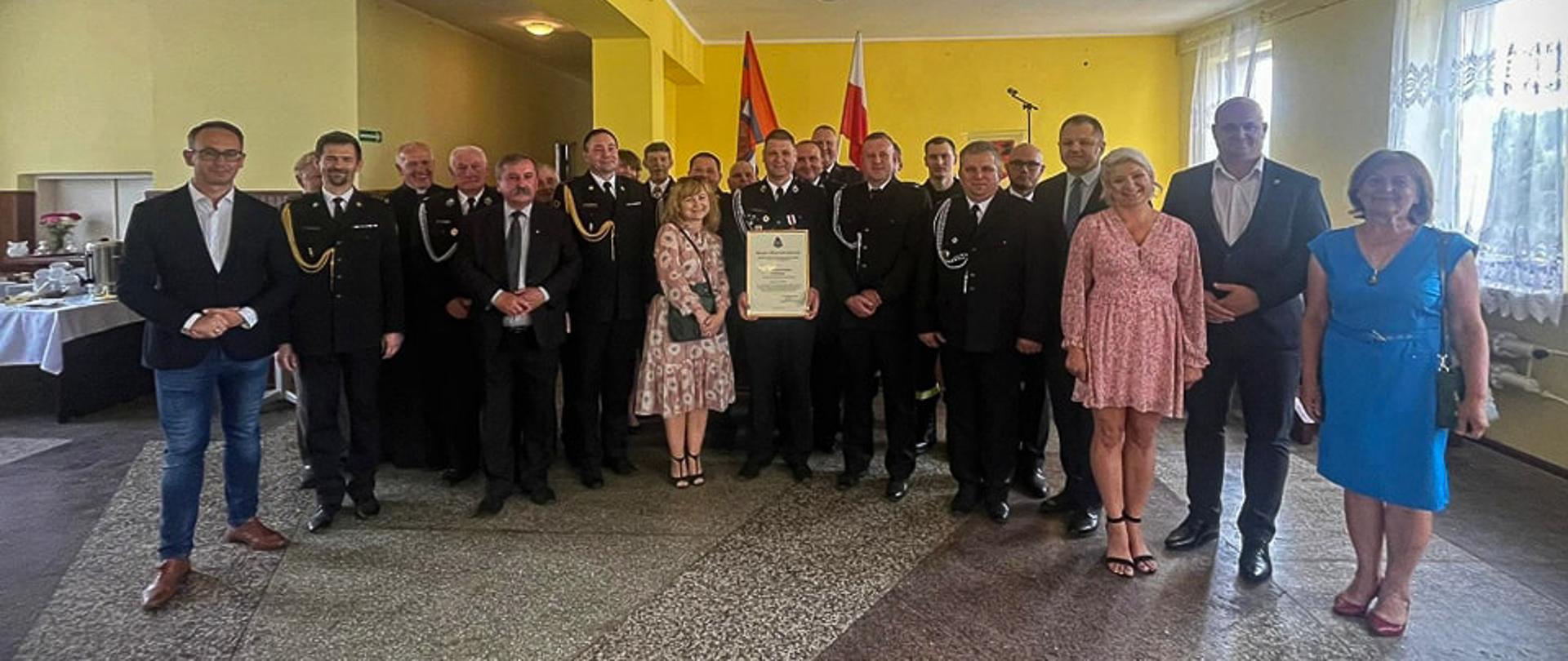uczestnicy uroczystości druhowie strażacy politycy i zaproszenie goście pozują do zdjęcia w sali remizy