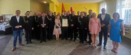uczestnicy uroczystości druhowie strażacy politycy i zaproszenie goście pozują do zdjęcia w sali remizy
