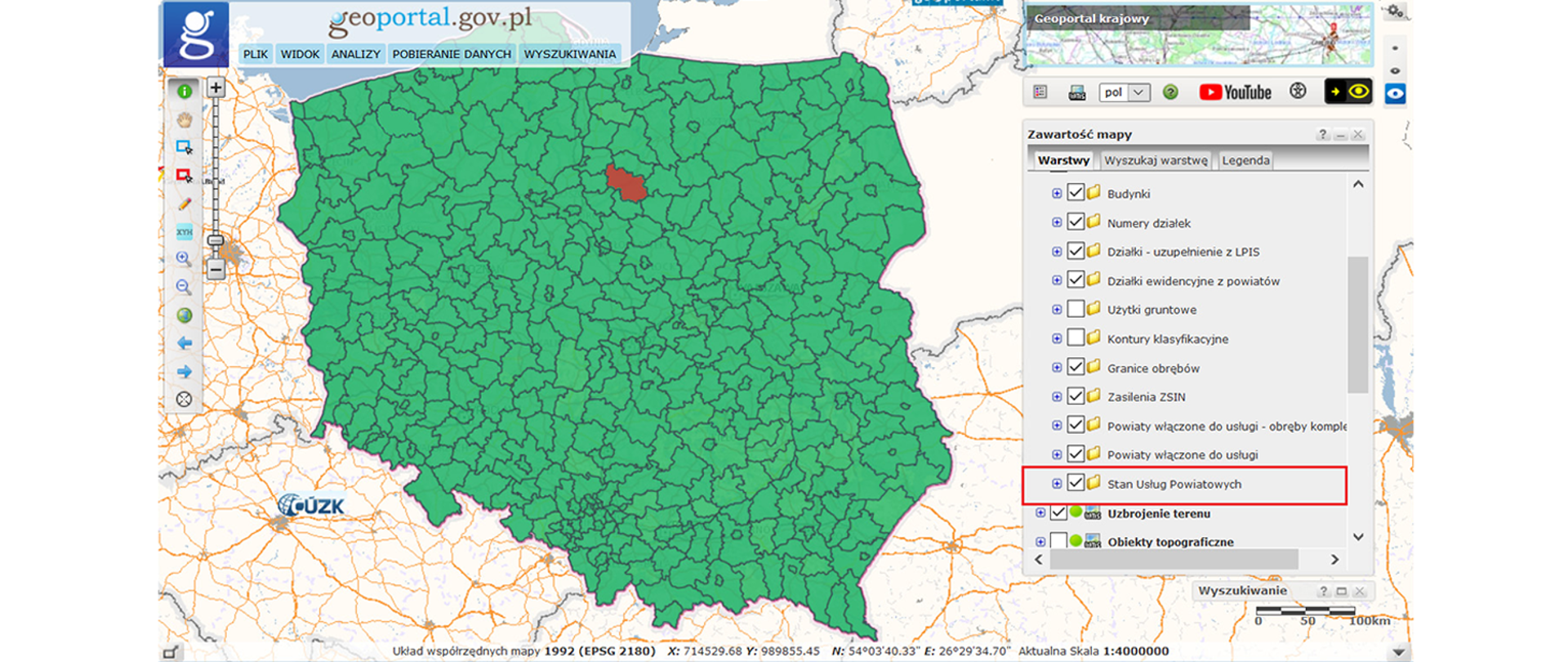 Ilustracja przedstawia zrzut ekranu ze strony geoportal.gov.pl, na którym znajduje się mapa Polski z podziałem na powiaty. Powiat brodnicki oznaczony jest kolorem czerwonym, pozostałe zaś na zielono.