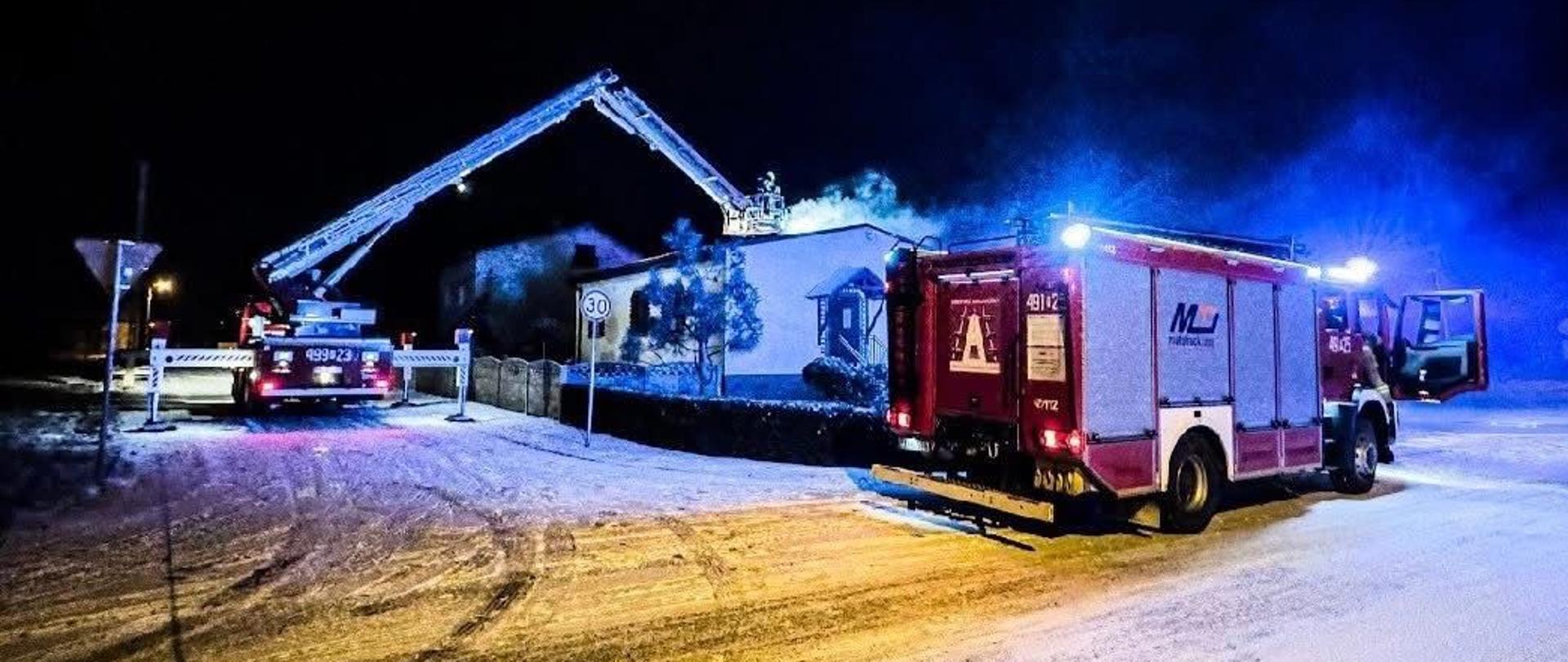 Pożar sadzy w przewodzie kominowym. Strażacy prowadzą działania z uzyciem podnośnika hydraulicznego. Na zdjęciu budynek jednorodzinny, Widoczna duża ilość dymu. Trwają działania gaśnicze.
