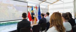 Na mównicy kobieta przemawia do sali, z tyłu widać flagę Mołdawii, Polski, Unii Europejskiej i Kolegium Europy