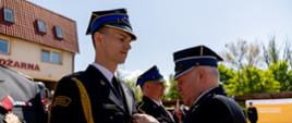 Strażak w umundurowaniu galowym otrzymuje odznaczenie przypinane do munduru.