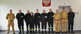 sala wykładowa komendy psp w brzezinach zdjęcie pamiątkowe uczestników szkolenia oraz wykładowców sród których jest również komendant powiatowy psp w brzezinach oraz funkcjonariusz komendy wojewódzkiej psp w łodzi wszyscy stoją w szeregu w umundurowaniu służbowym