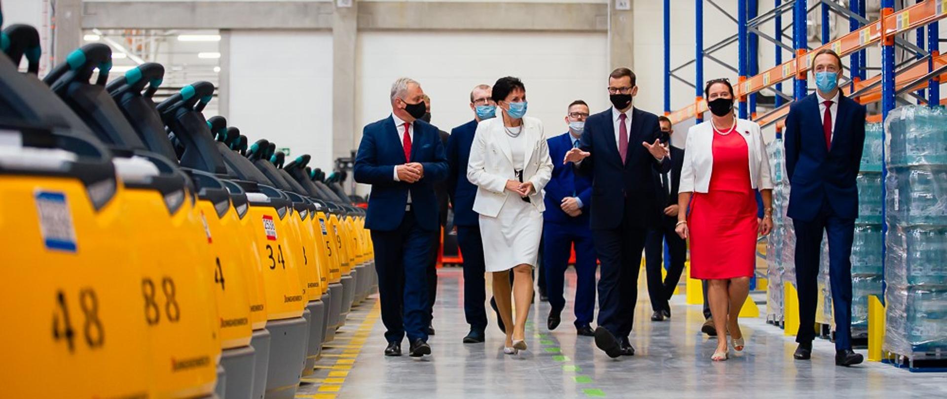 Premier oraz właściciele idą w siedzibie firmy.