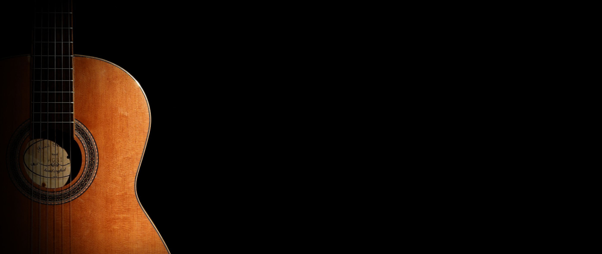 Pudło rezonansowe gitary klasycznej po lewej stronie na czarnym tle