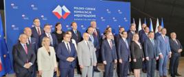 W dużej sali pod ścianką z napisem Polsko-czeskie konsultacje międzyrządowe stoi grupa około dwudziestu elegancko ubranych osób.