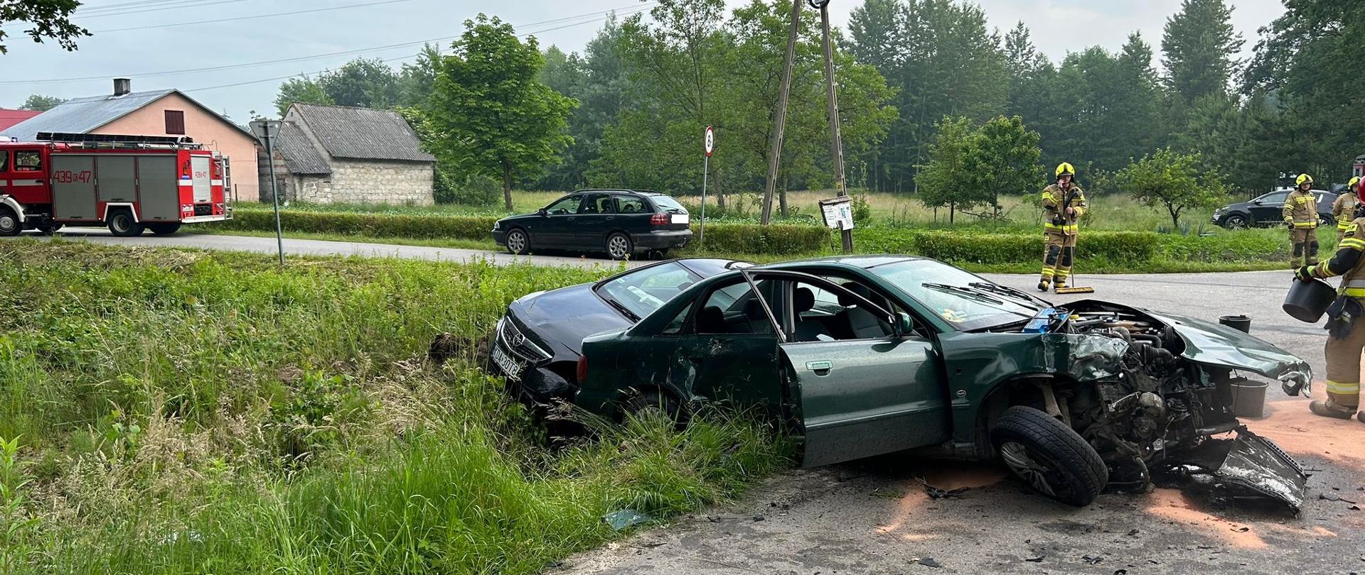 Na zdjęciu widać zderzenie dwóch samochodów osobowych,jeden jest w rowie, drugi stoi prostopadle do jezdni, na dordze rolznae płyny eksploatacyjne.