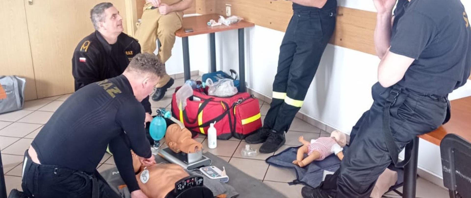 Strażacy przy manekinie podczas szkolenia.