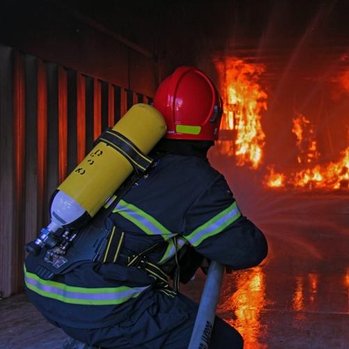 Strażak podczas ćwiczeń w kabinie z ogniem gasi go