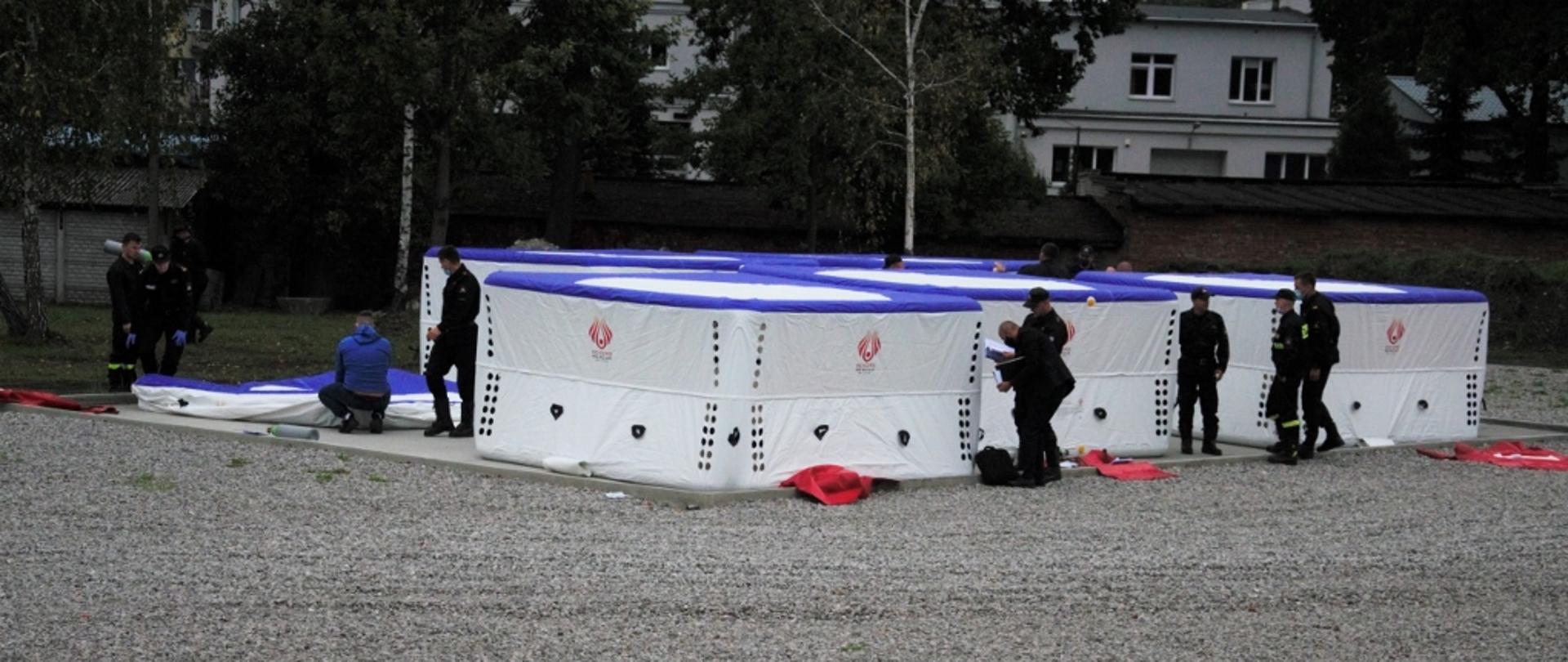 Zdjęcie przedstawia kilka rozstawionych skokochronów przy których są strażacy obsługujący sprzęt.