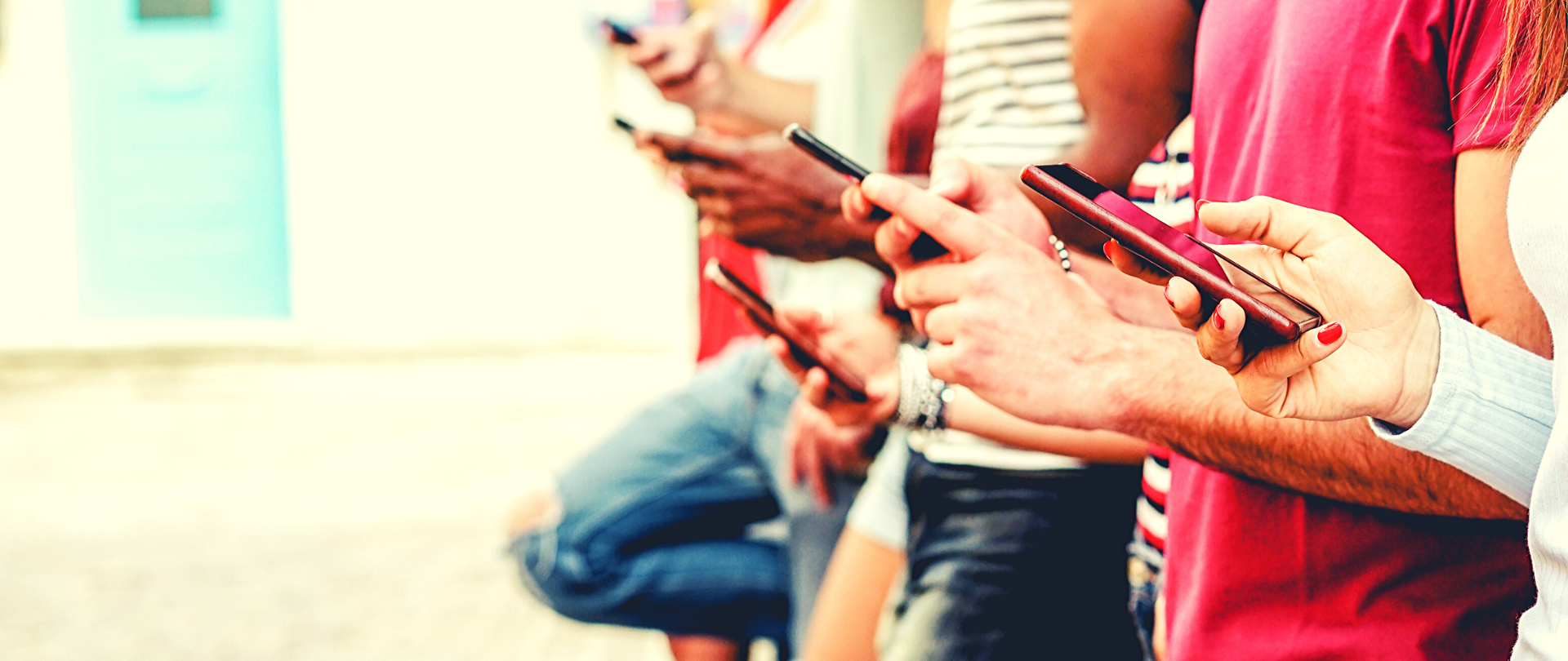 Wąskie ujęcie grupy ludzi (od pasa do kolan) ze smartfonami w rękach.
