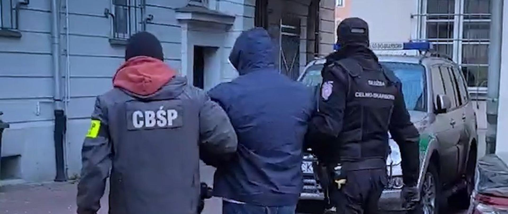 Funkcjonariusze Centralnego Biura Śledczego Policji i Służby Celno-Skarbowej prowadzą zatrzymanego.