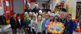 dzieci na garażu zapoznają się ze sprzętem jakim dysponują mińscy strażacy w tle komendant powiatowy PSP i kapelan strażaków