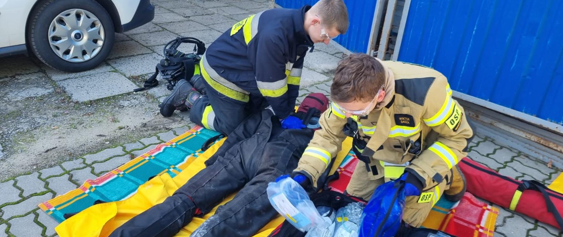 Strażacy OSP udzielają pomocy poszkodowanemu (fantomowi) podczas ćwiczeń w szpitalu.