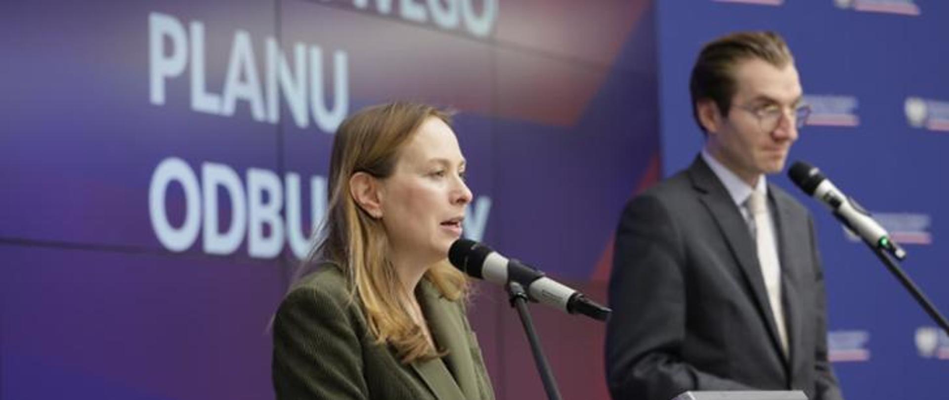 In the photo, Minister Katarzyna Pełczyńska-Nałęcz and Deputy Minister Jan Szyszko stand on the stage in front of microphones