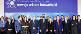 Minister Rozwoju i Technologii Piotr Nowak na zdjęciu grupowym z uczestnikami uroczystości podpisania porozumienia o współpracy na rzecz rozwoju sektora fotowoltaiki, po lewej stronie przy ministrze stoi wiceminister Klimatu i Środowiska Ireneusz Zyska 