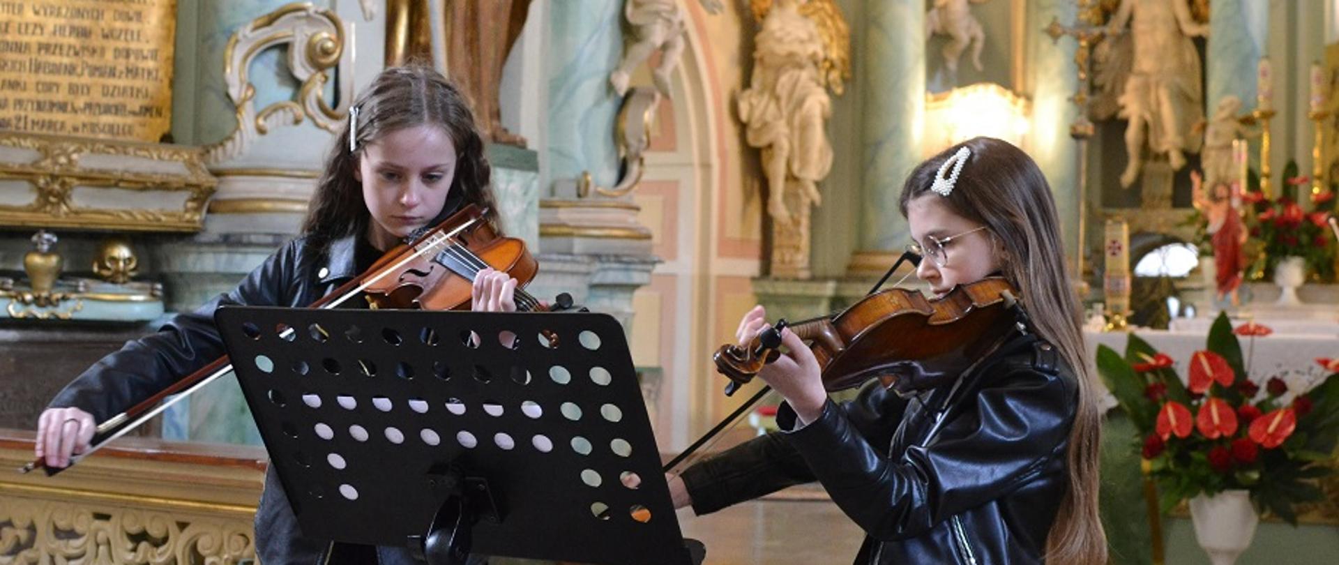 dwie uczennice grające na skrzypcach w kościele