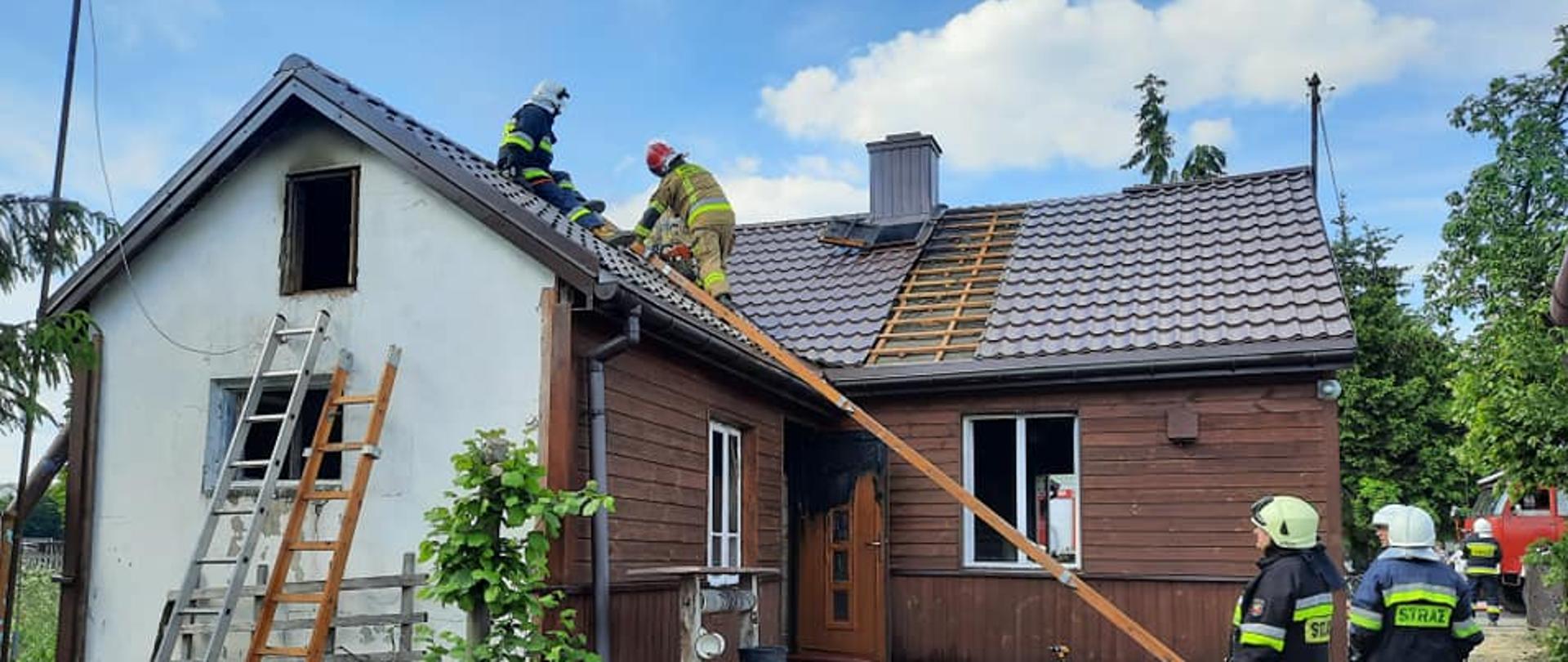 Strażacy po ugaszeniu pożaru demontują blachodachówkę.