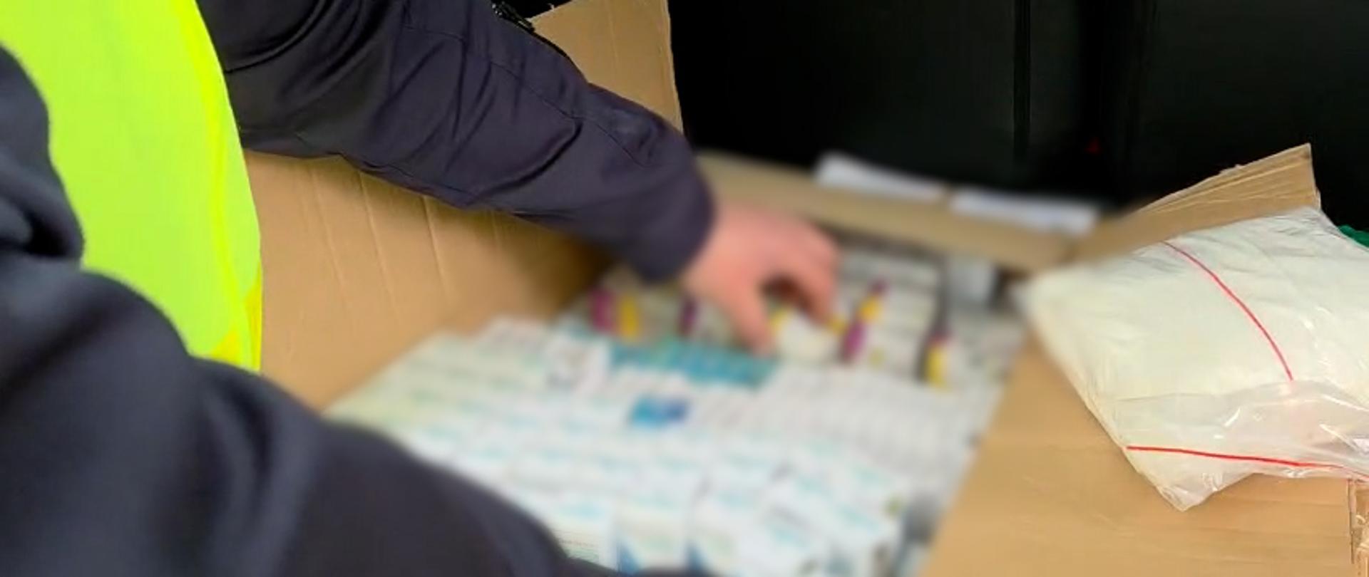 Funkcjonariusz Służby Celno-Skarbowej podczas sprawdzania zawartości kartonu.