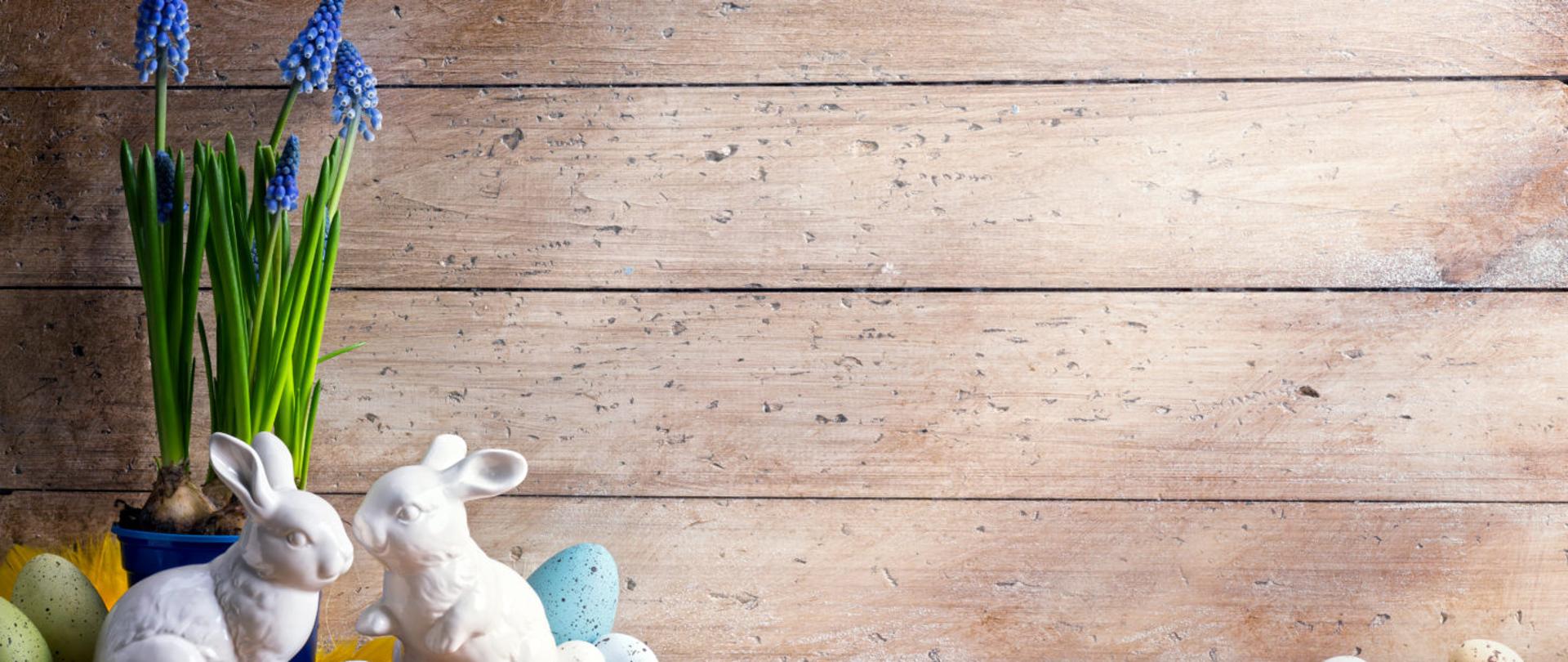 zajączki porcelanowe i jajka wielkanocne na tle desek
