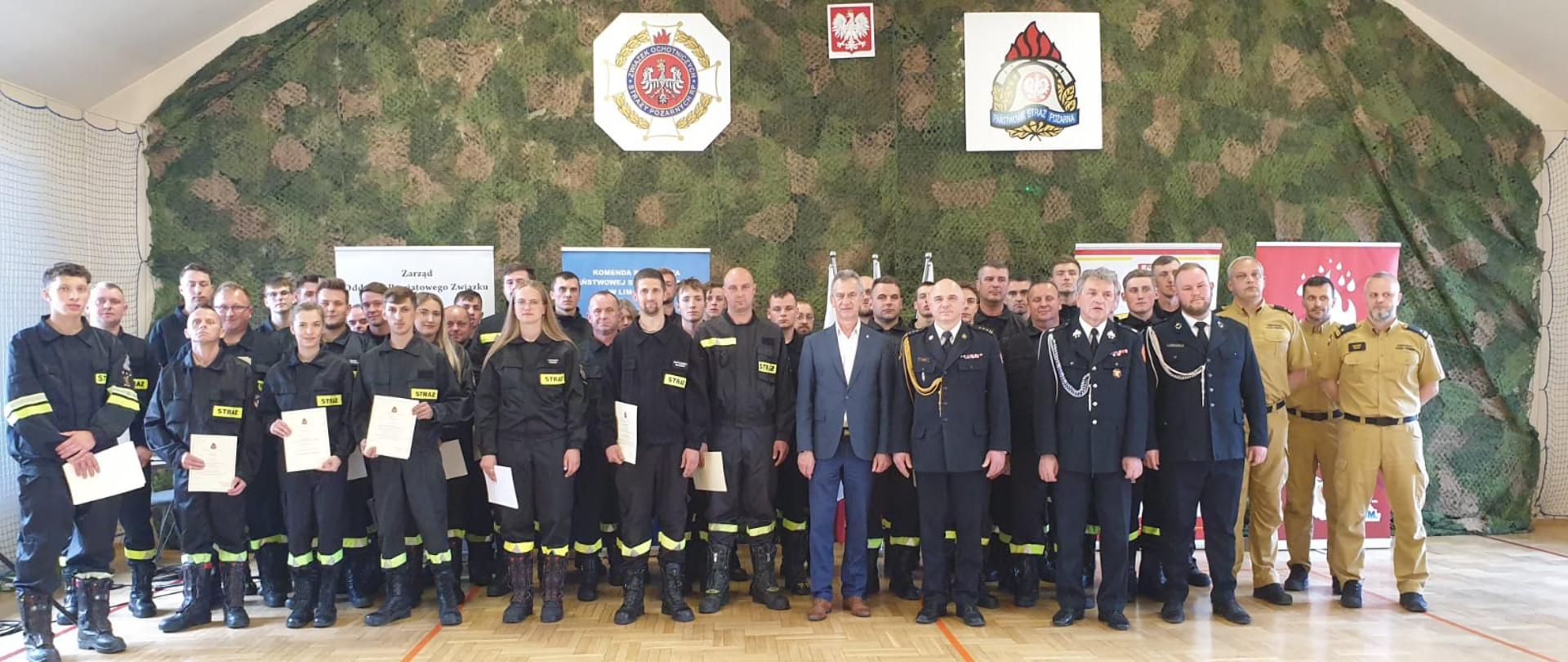 Zdjęcie przedstawia wspólne zdjęcie Starosty powiatowego, Komendantów PSP I OSP, funkcjonariuszy PSP oraz druhów OSP na uroczystym zakończenie szkolenia strażaków ratowników. 