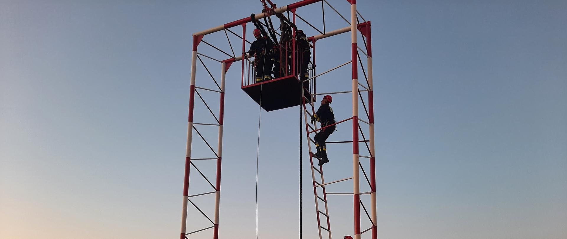Strażacy w kombinezonach podczas ćwiczeń wysokościowych