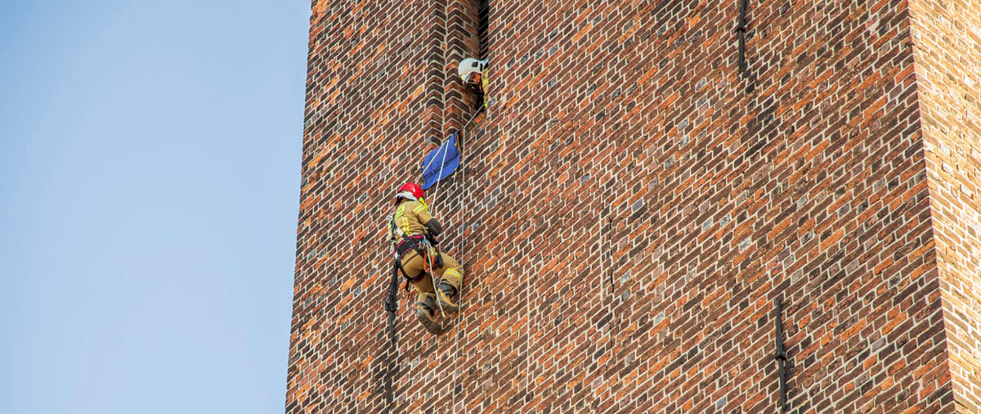 Strażak PSP dostaje się do osoby która zawisła na linie 