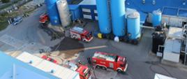 Samochody ratowniczo-gaśnicze biorące udział w akcji gaśniczej widziane z dachu budynku.
