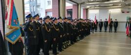 Zdjęcie przedstawia stojących strażacy ze sztandarami ubrani w mundury OSP, goście honorowi i zaproszenie w mundurach oraz osoby cywilne