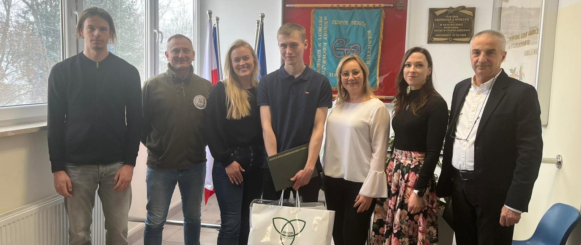 Nagrodzony uczeń pozuje do zdjęcia z dyrektorem, opiekunami konkursu oraz przedstawicielami MODR 