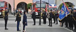 Przegląd pododdziałów w trakcie uroczystości. W tle samochody pożarnicze