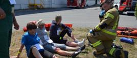 Zdjęcie przedstawia osoby poszkodowane w trakcie ćwiczeń w punkcie medycznym i strażaka udzielającego kwalifikowanej pierwszej pomocy