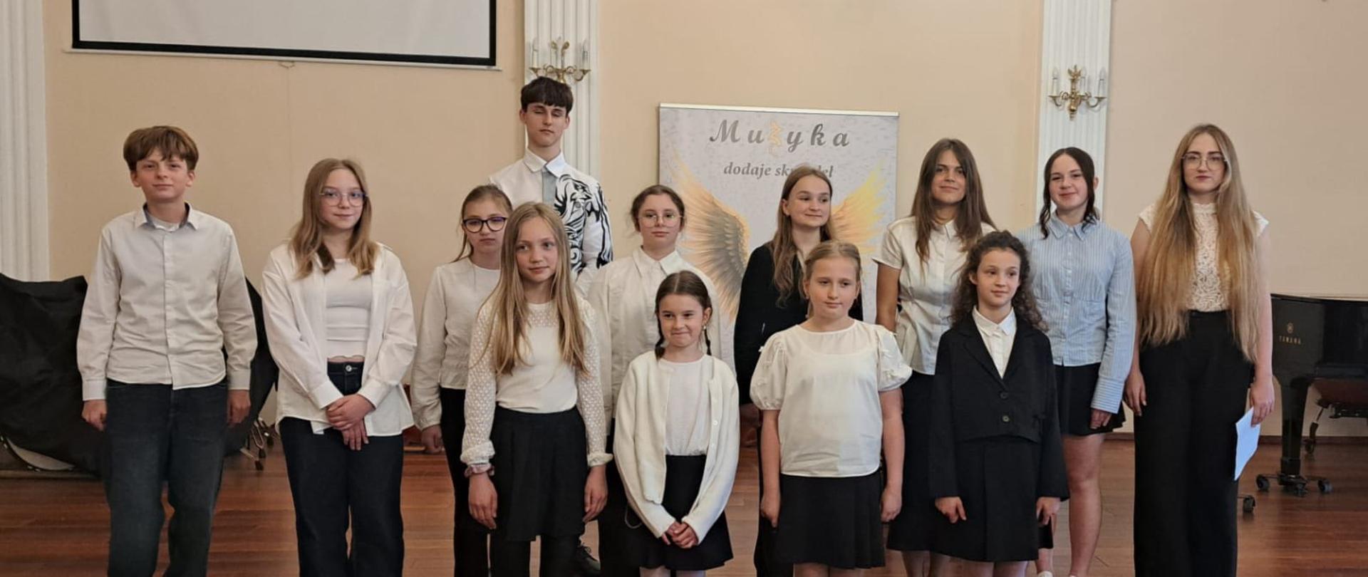 Uczniowie klasy I cyklu 4 na scenie w sali koncertowej podczas popisu w Państwowej Szkole Muzycznej I st. w Lublińcu