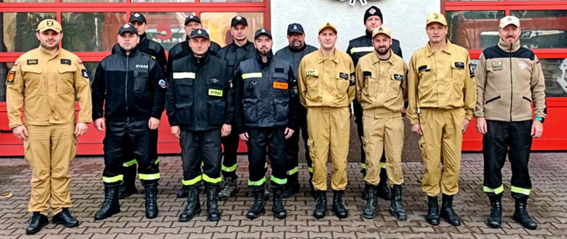 Zdjęcie przedstawia kierownika szkolenia z Komendy Powiatowej PSP w Ustrzykach Dolnych oraz biorących udział w szkoleniu KDRa z jednostek OSP. Zdjęcie wykonane jest przed garażami JRG. 