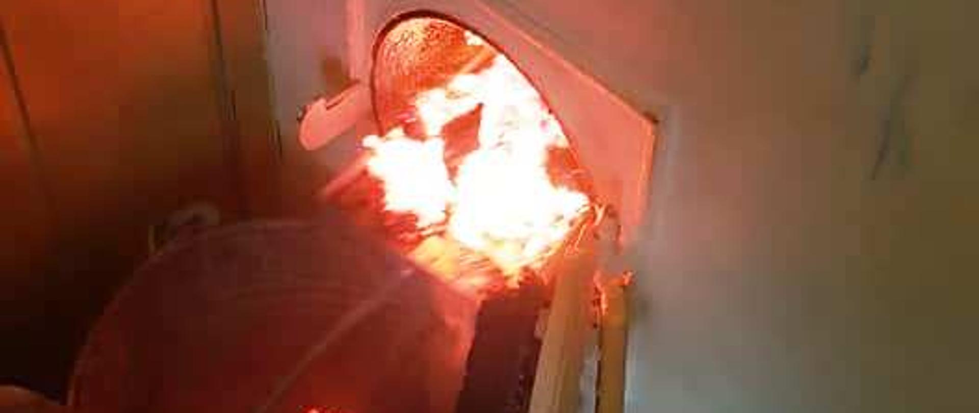 Paląca się sadza w otworze rewizyjnym komina oraz żarząca się w wiaderku.