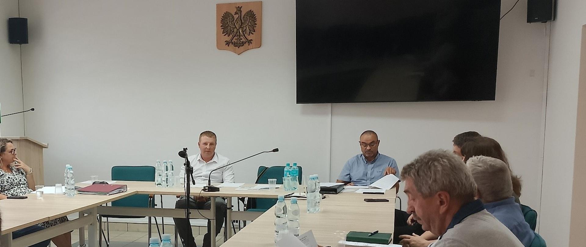 Na zdjęciu widoczna grupa osób siedząca przy stole , czytająca dokumenty