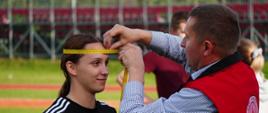 Na zdjęciu widoczna kobieta w czarnej koszulce i sędzia dokonujący pomiaru jej głowy. Była to jedna z konkurencji drużynowej w XXXI Spartakiadzie HDK PCK w Ropie.