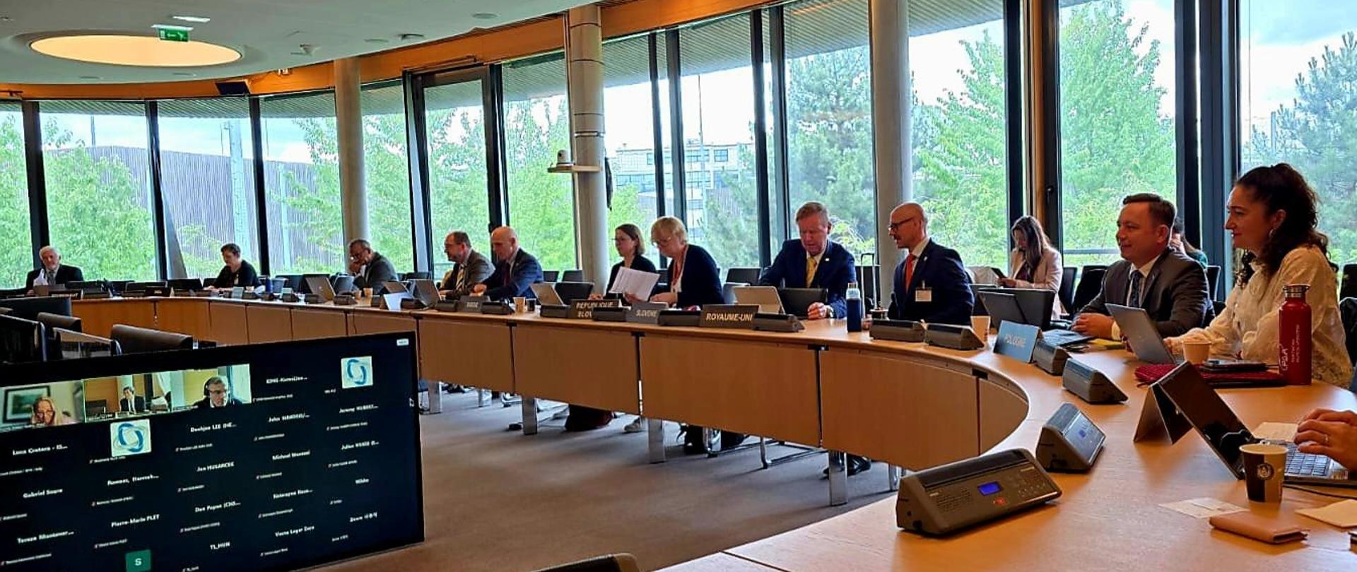 Meeting of the Committee for the Activities of Nuclear Regulators with the participation of PAA - participants sit in the room. A monitor with participants connected online is also visible