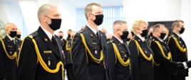 Funkcjonariusze Państwowej Straży Pożarnej stoją w rzędzie trzymając wyróżnienia.