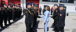 Wręczanie odznaczeń strażakom stojącym w szyku.