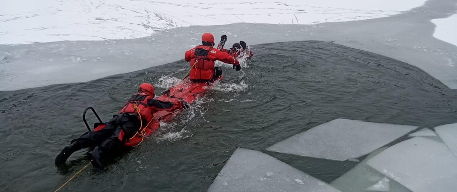 Na zdjęciu strażacy ćwiczą na zalodzonym zbiorniku wodnym