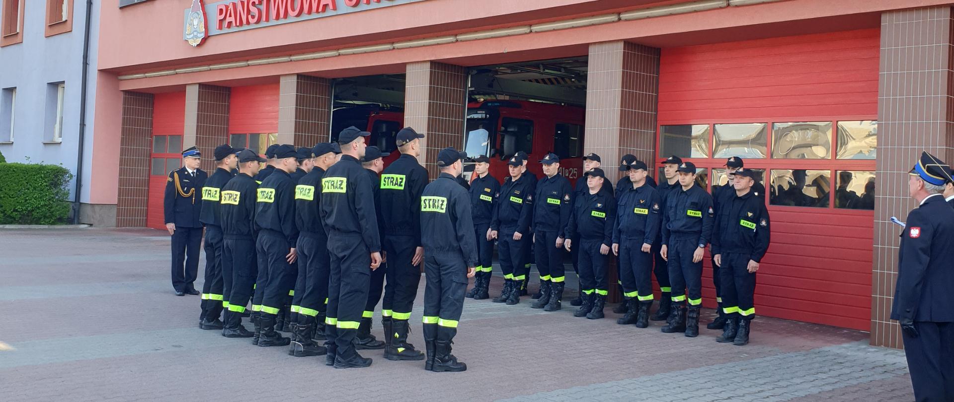 Zdjęcie wykonane w ciągu dnia przed JRG 1 w Kaliszu. Podłoże z kostki brukowej. Widać umundurowane osoby. Słonecznie.