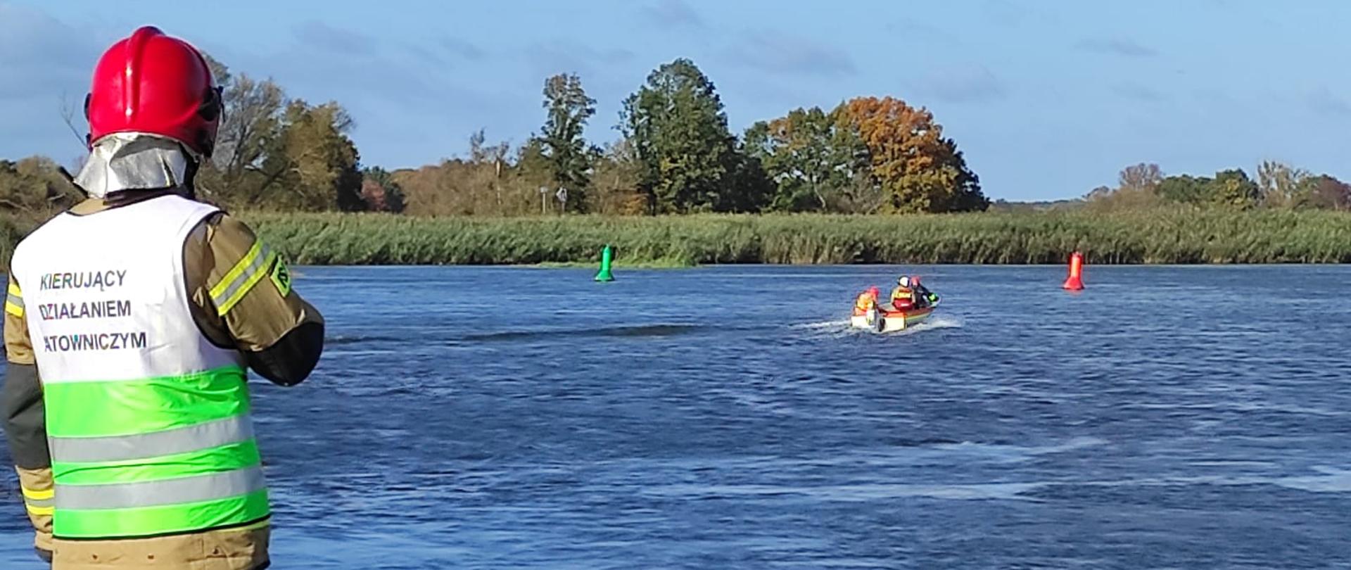 Strażak nadzorujący pracę łodzi na rzecze.