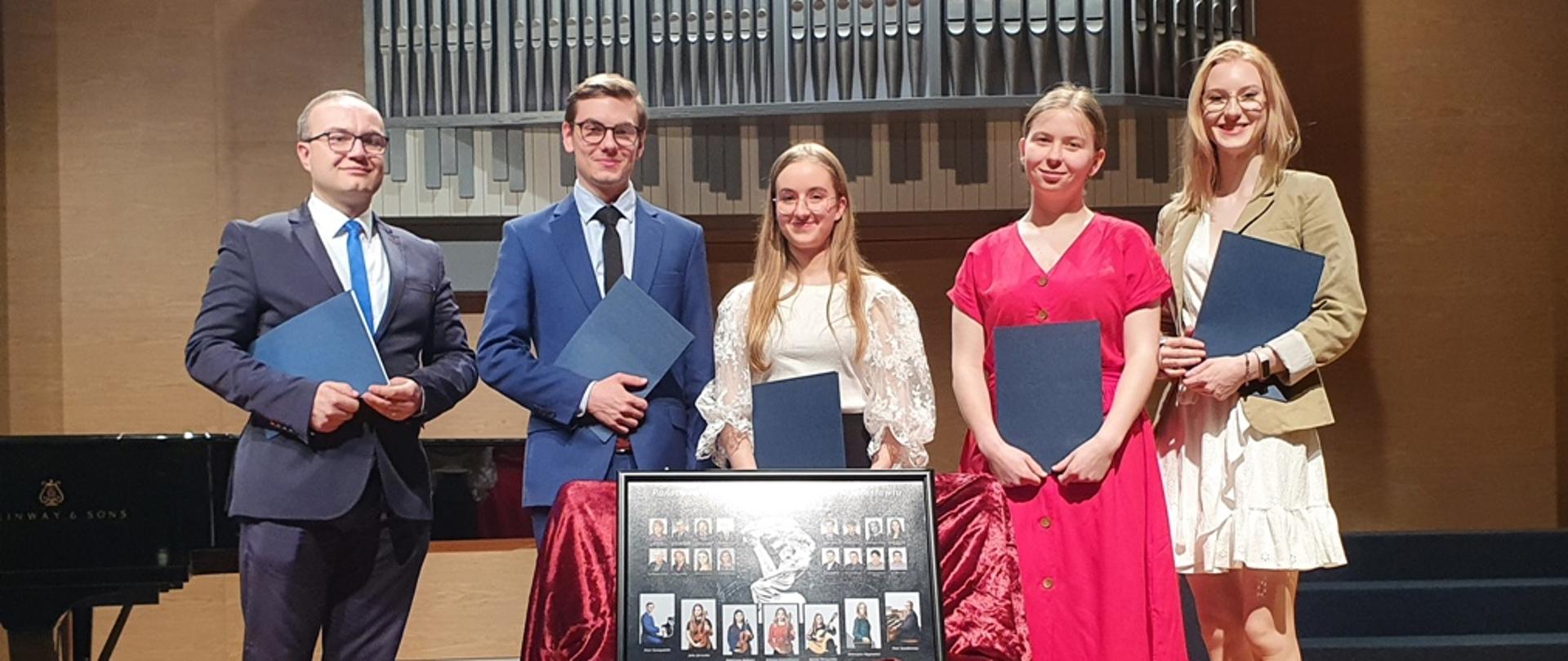Zdjęcie na scenie Sali Koncertowej ZPSM w Jarosławiu, od lewej: Piotr Sanakiewicz - klasa organów mgra Adriana Szczurka, Piotr Szczepański - klasa fortepianu dra Marcina Kasprzyka, Dorota Perczyńska - klasa gitary mgra Roberta Polańskiego, Julia Zarzecka - klasa skrzypiec mgra Krzysztofa Swobody, Katarzyna Wygnaniec - klasa śpiewu mgr Renaty Johnson-Wojtowicz